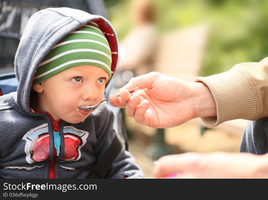 Cute boy eating yogurt outdoors. Cute boy eating yogurt outdoors