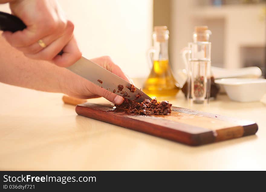 Chef cutting sundried tomatoes on board