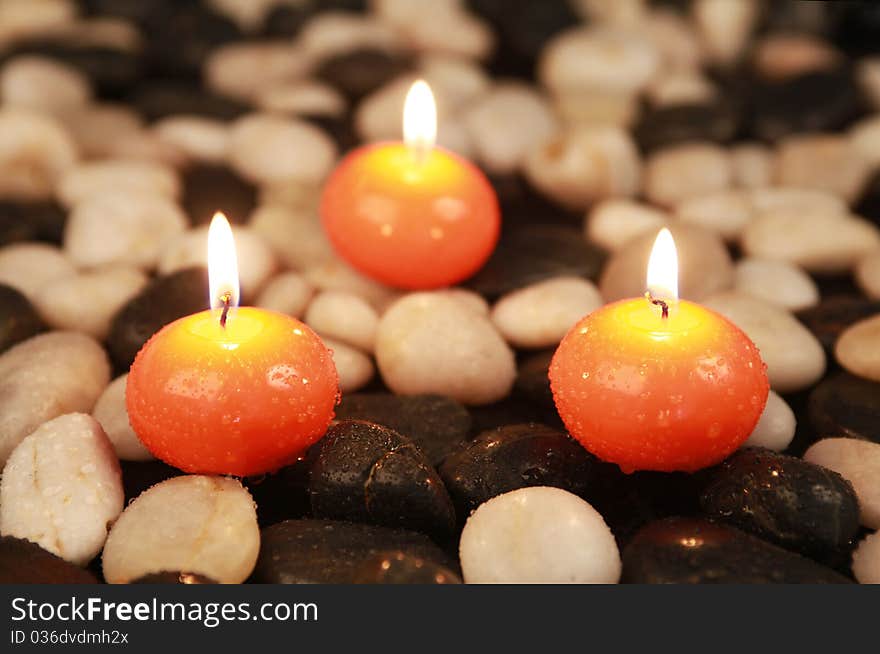 Triangle of orange candles on stones