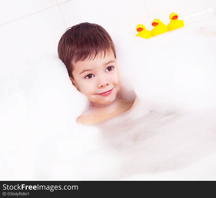 Cute four year old boy taking a relaxing bath with foam. Cute four year old boy taking a relaxing bath with foam