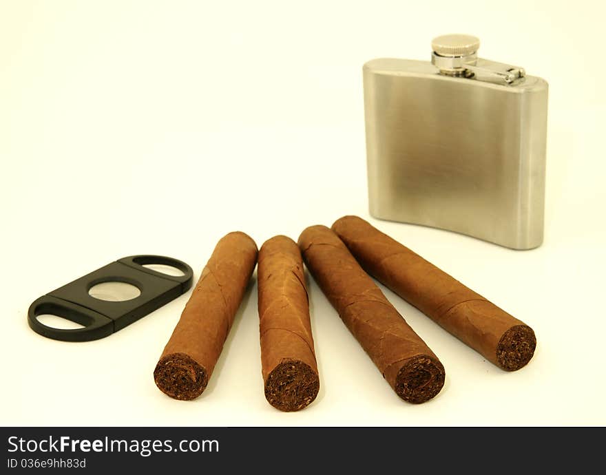 Close up of  4 cigars, cigar cutter and hip flask. Close up of  4 cigars, cigar cutter and hip flask