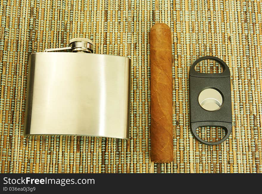 Close up of cigar, cigar cutter and hip flask. Close up of cigar, cigar cutter and hip flask