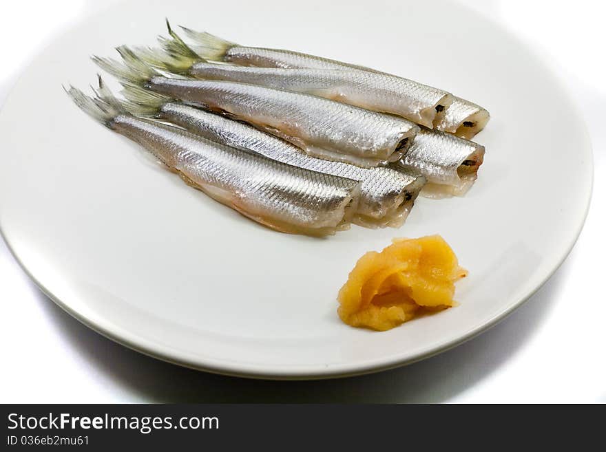 Freh small scale fish with caviar on white plate