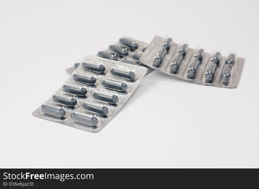 Close up of two grey pills on white background