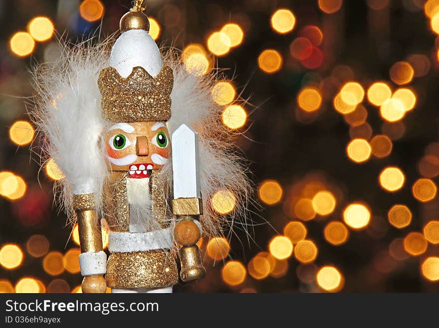 Christmas holiday ornament figurine in the foreground and Christmas tree lights (bokeh) in the background. Christmas holiday ornament figurine in the foreground and Christmas tree lights (bokeh) in the background