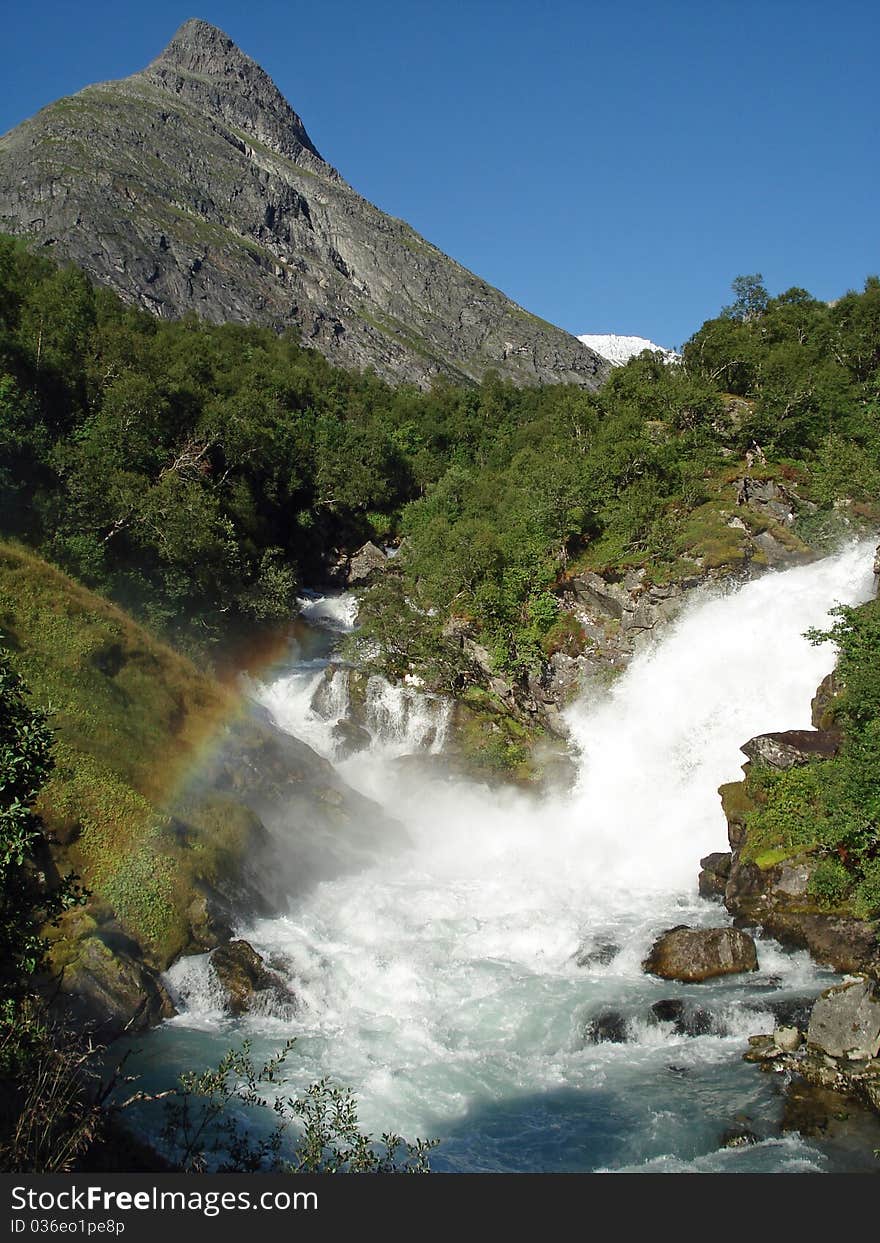 Waterfall in the Lodalen Valley, lake Lovatnet. Loen, Stryn, Norway. (Blurred background). The Lodalen valley has a dramatic history. Giant boulders have twice (1905 and 1936) broken off Mount Ramnefjell and fallen into the Lovatnet lake, creating tidal waves that destroyed the villages of Nesdal and Bodal. Waterfall in the Lodalen Valley, lake Lovatnet. Loen, Stryn, Norway. (Blurred background). The Lodalen valley has a dramatic history. Giant boulders have twice (1905 and 1936) broken off Mount Ramnefjell and fallen into the Lovatnet lake, creating tidal waves that destroyed the villages of Nesdal and Bodal.