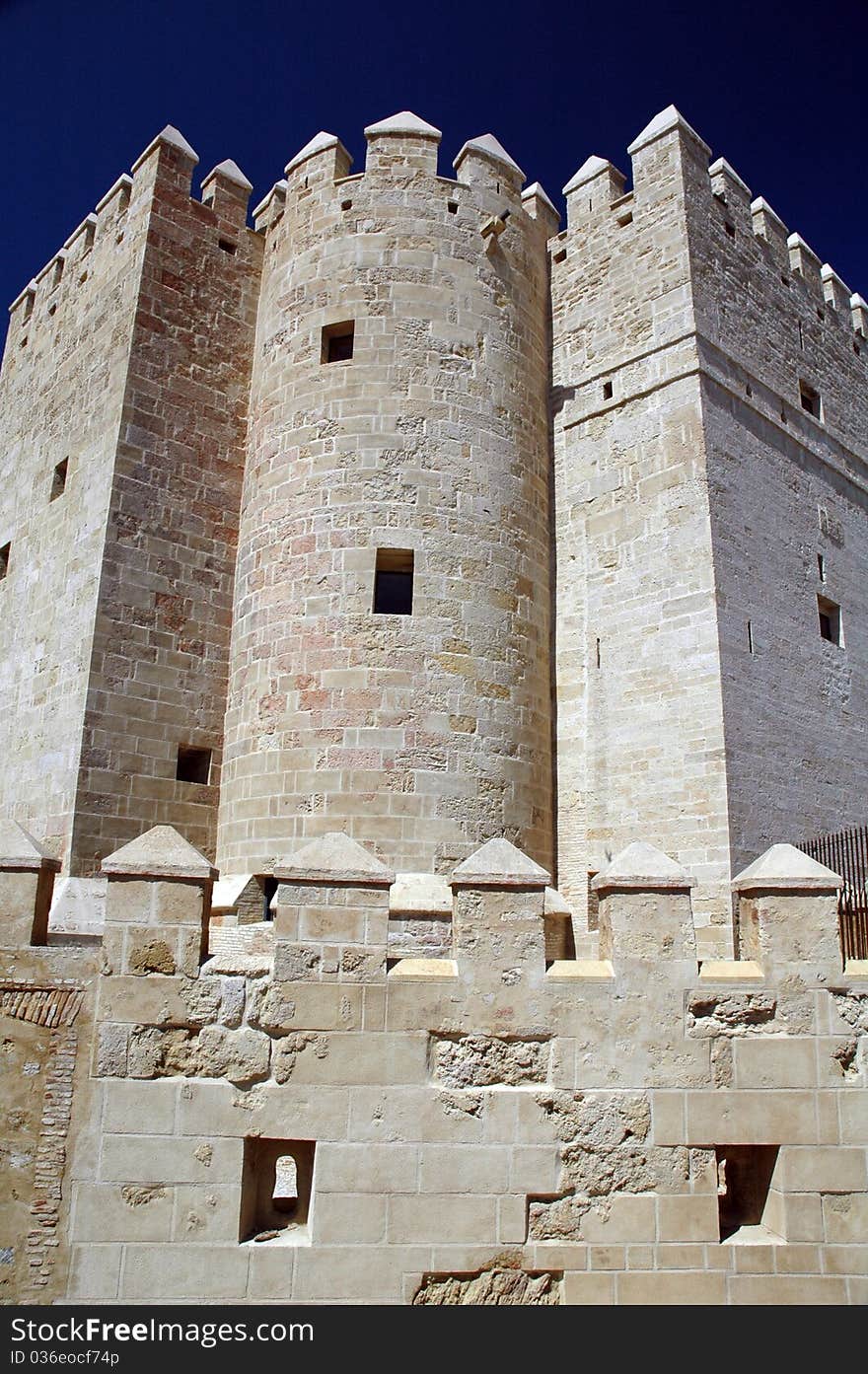 Fortress wall in Seville (Sevilla), Spain at the Real Alcazar with parapets. Blue sky background.