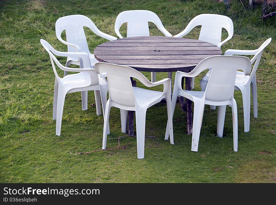 White folding chairs and a table on a background of grass. White folding chairs and a table on a background of grass