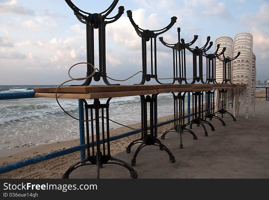 Stacked tables and chairsagainst the backdrop of the sea