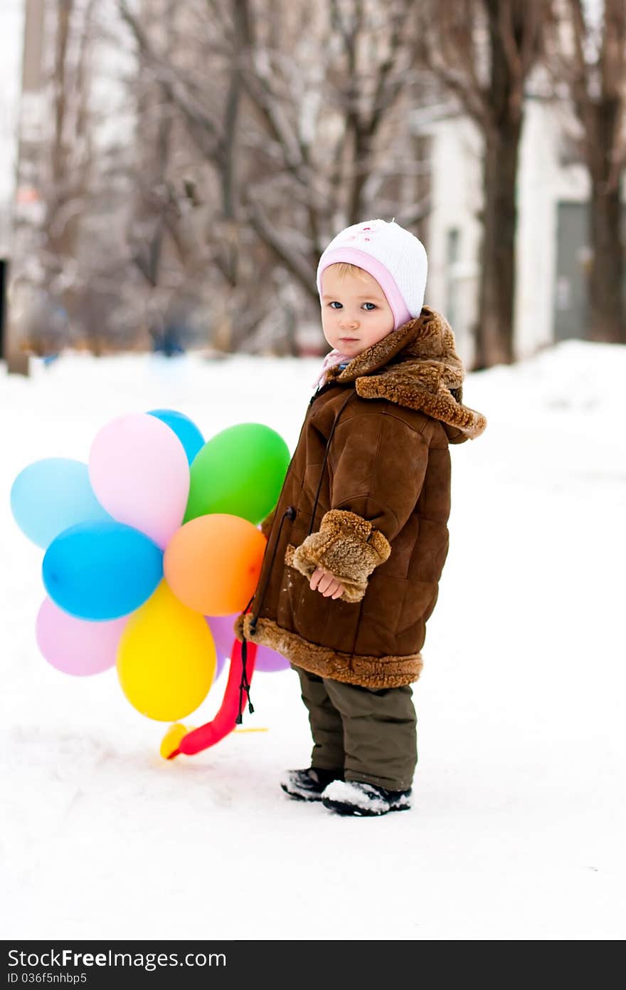 Beautiful girl playing with balloons outdoor in winter