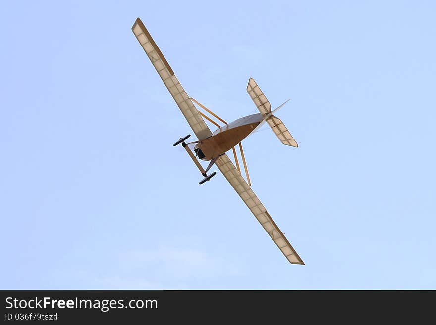 Old propeller in flight over blue sky.