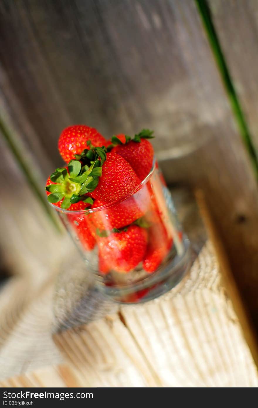 Strawberry in glass in front of wood and on wood, village raw food