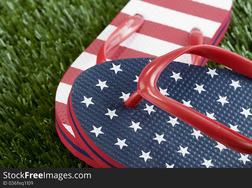 A pair of USA stars and strips flipflops in the grass. A pair of USA stars and strips flipflops in the grass