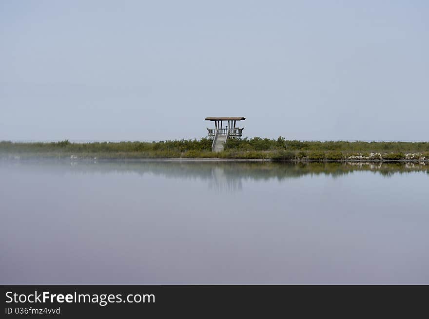 An observation tower in a wildlife preserve in Florida in a light fog reflecting in water. An observation tower in a wildlife preserve in Florida in a light fog reflecting in water.