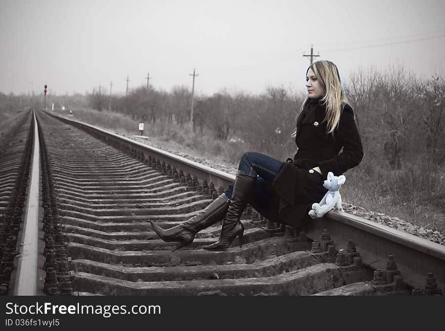 The Girl Sits On Rails With A Toy