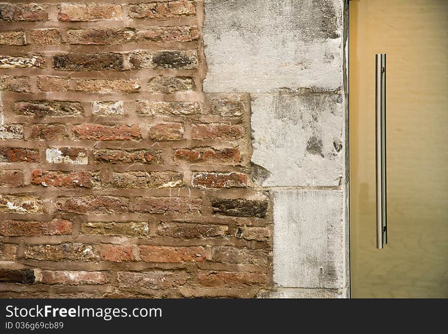 Close up of an old ancient brick wall of an old european building with a part of a glass door on the right side. A perfect combination of old and new. Close up of an old ancient brick wall of an old european building with a part of a glass door on the right side. A perfect combination of old and new