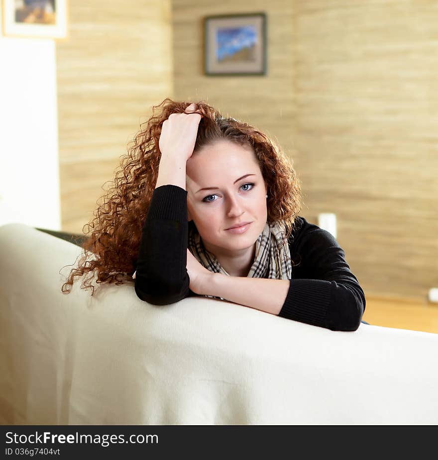 A young red hair girl sitting on the sofa at home alone. A young red hair girl sitting on the sofa at home alone