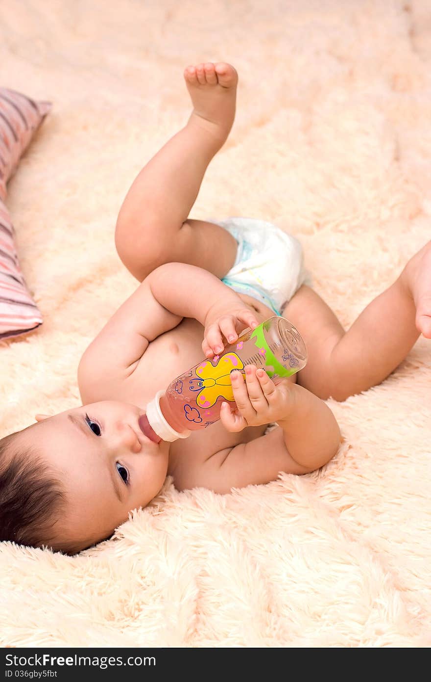 Little caucasian boy drinking from the bottle