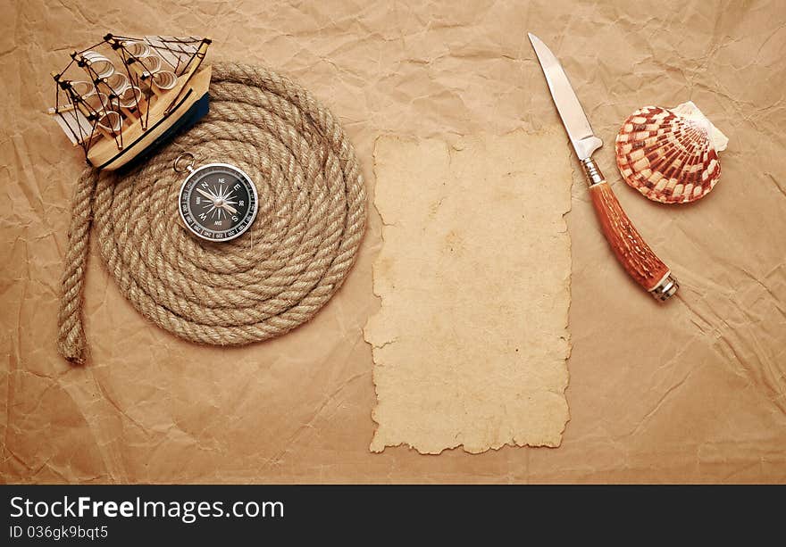 Rope coil, decorative knife and model classic boat on old paper. Rope coil, decorative knife and model classic boat on old paper