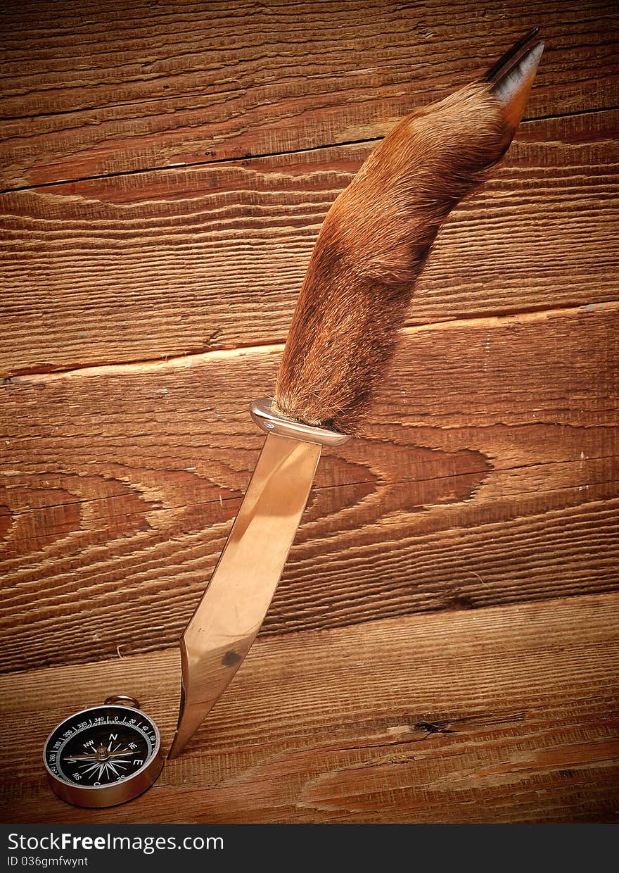 Knife and compass on wood background