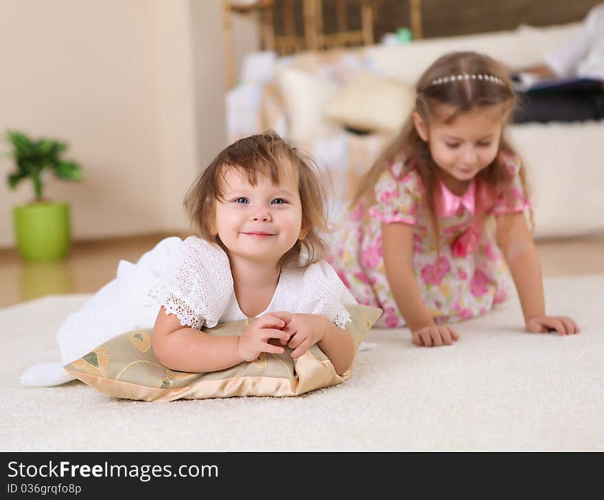 Two little sisters together playing on the floor of a livingroom