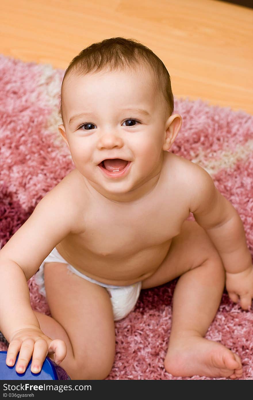 Smiling caucasain baby sitting on the carpet