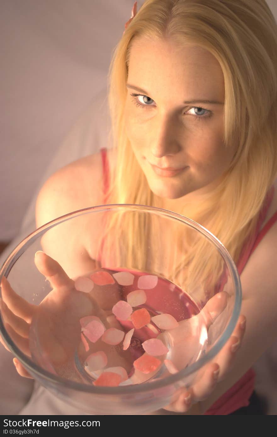 Young woman holding a glass bowl filled with water and pink petals. Young woman holding a glass bowl filled with water and pink petals