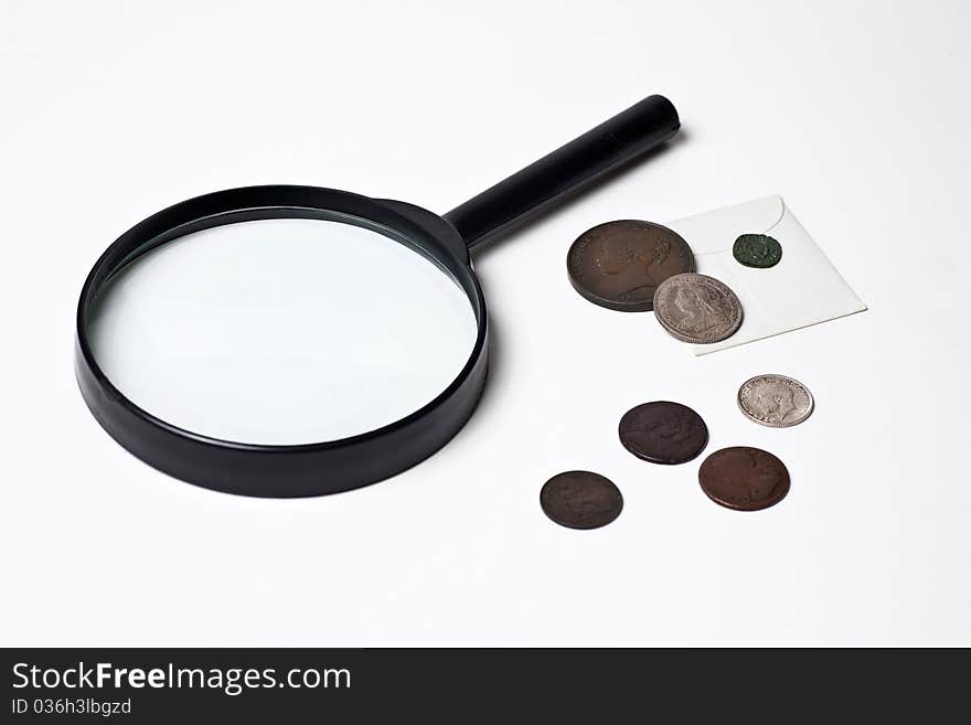 A selection of old British coins and a magnifying glass. A selection of old British coins and a magnifying glass.