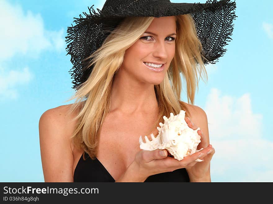 blond woman posing on the beach holding a shell. blond woman posing on the beach holding a shell