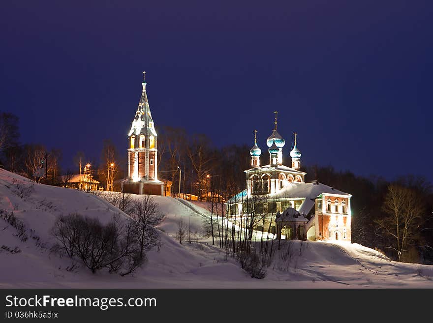 Brightly illuminated church on the bank of the frozen river