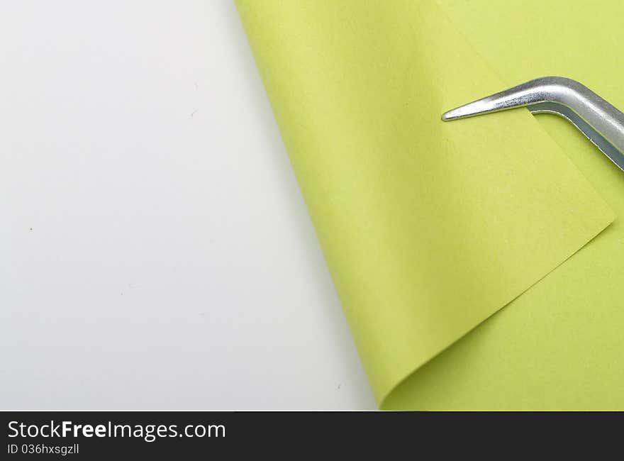 Green piece of paper is bent tweezers