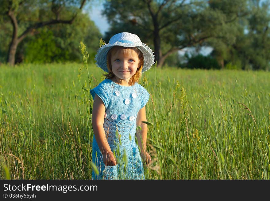 Cute little girl in hat in green grass field. Cute little girl in hat in green grass field