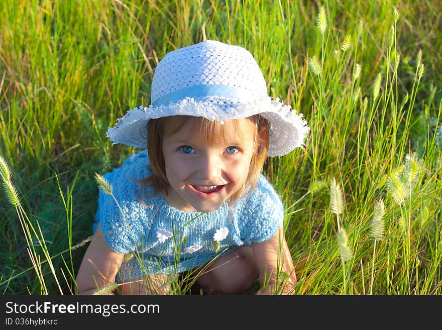 Cute little girl in hat in green grass field. Cute little girl in hat in green grass field