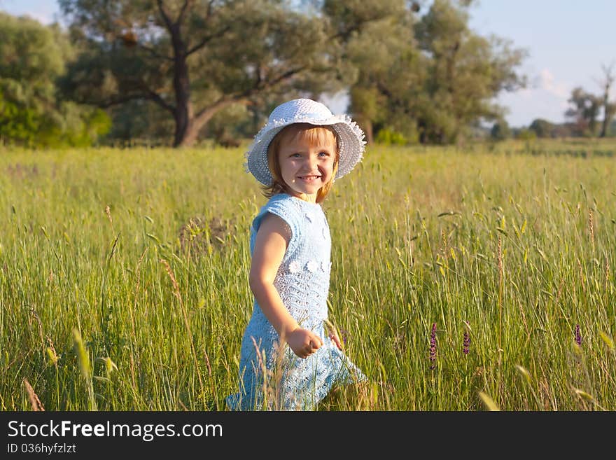 Cute little girl in hat in green grass field. Cute little girl in hat in green grass field