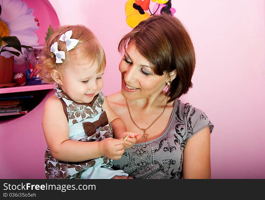 Young mum holds the small daughter on hands, they communicate with each other at home. Young mum holds the small daughter on hands, they communicate with each other at home