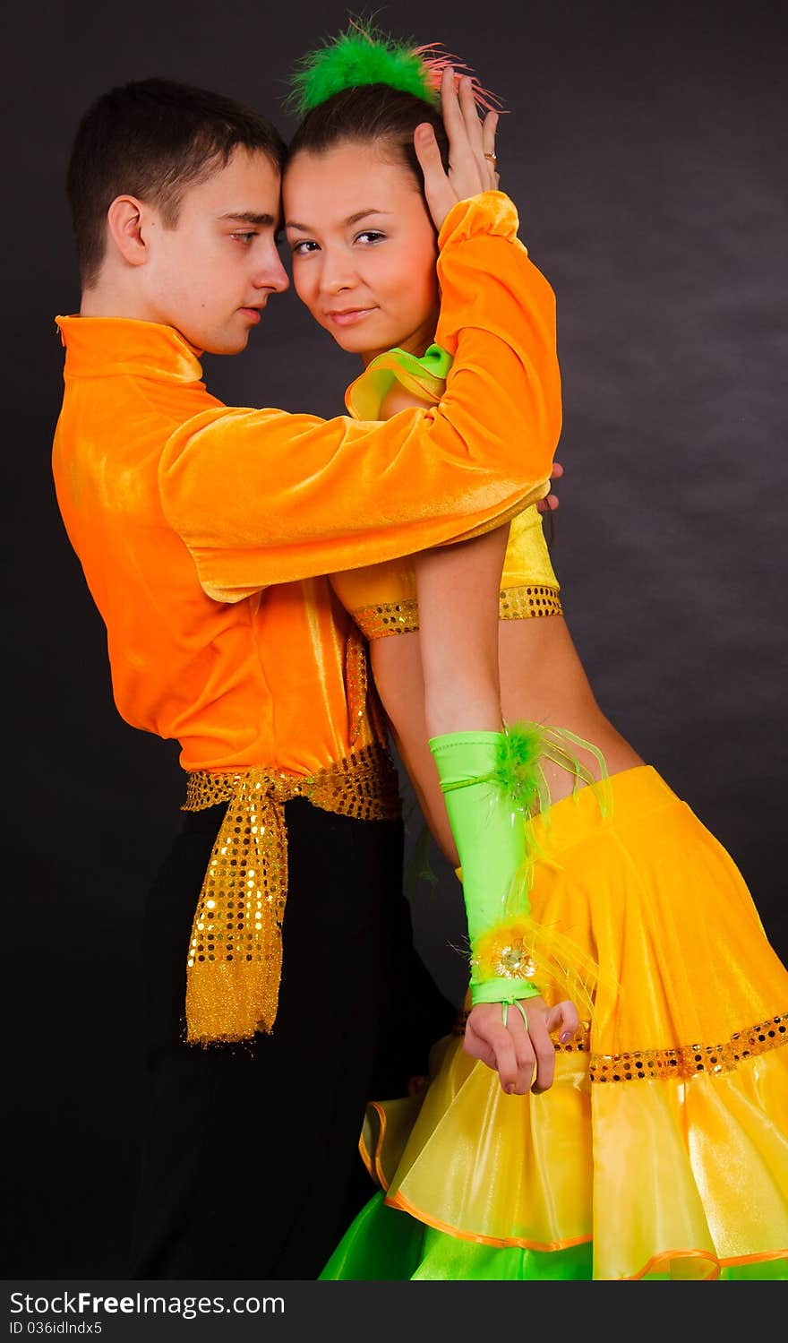 A beautiful young pair in good-looking suits dances on a dark background. A beautiful young pair in good-looking suits dances on a dark background