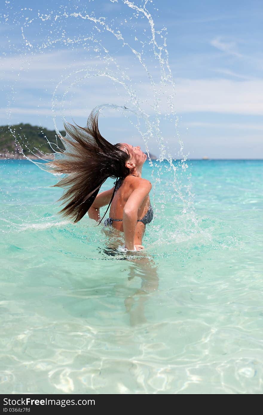 Lovely girl in sea water creates a splash