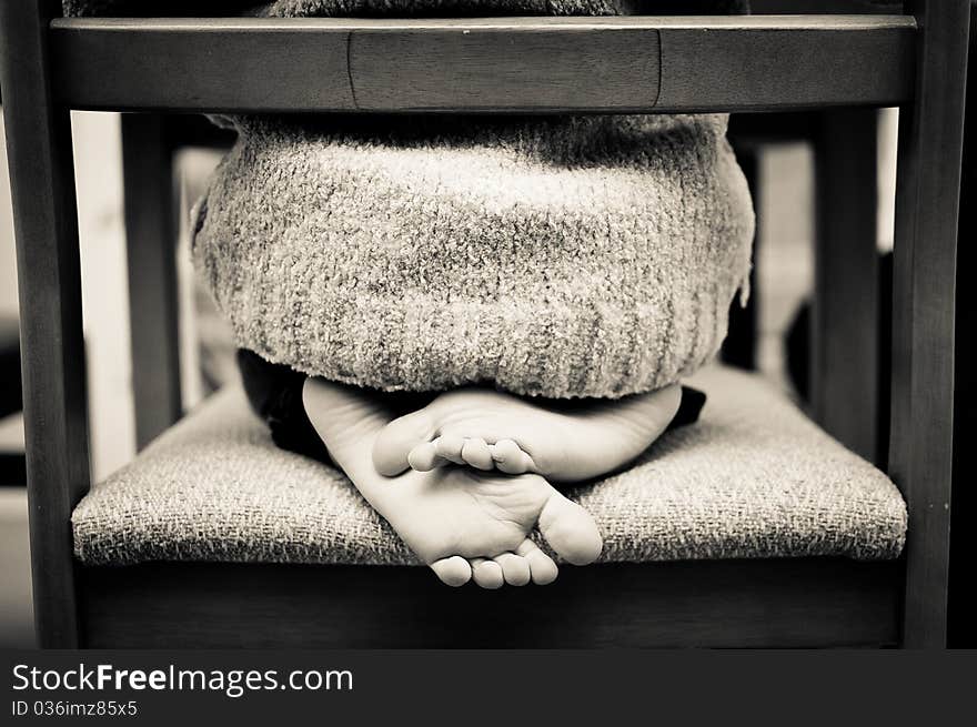 Child sat cross legged on a chair in black and white. Child sat cross legged on a chair in black and white