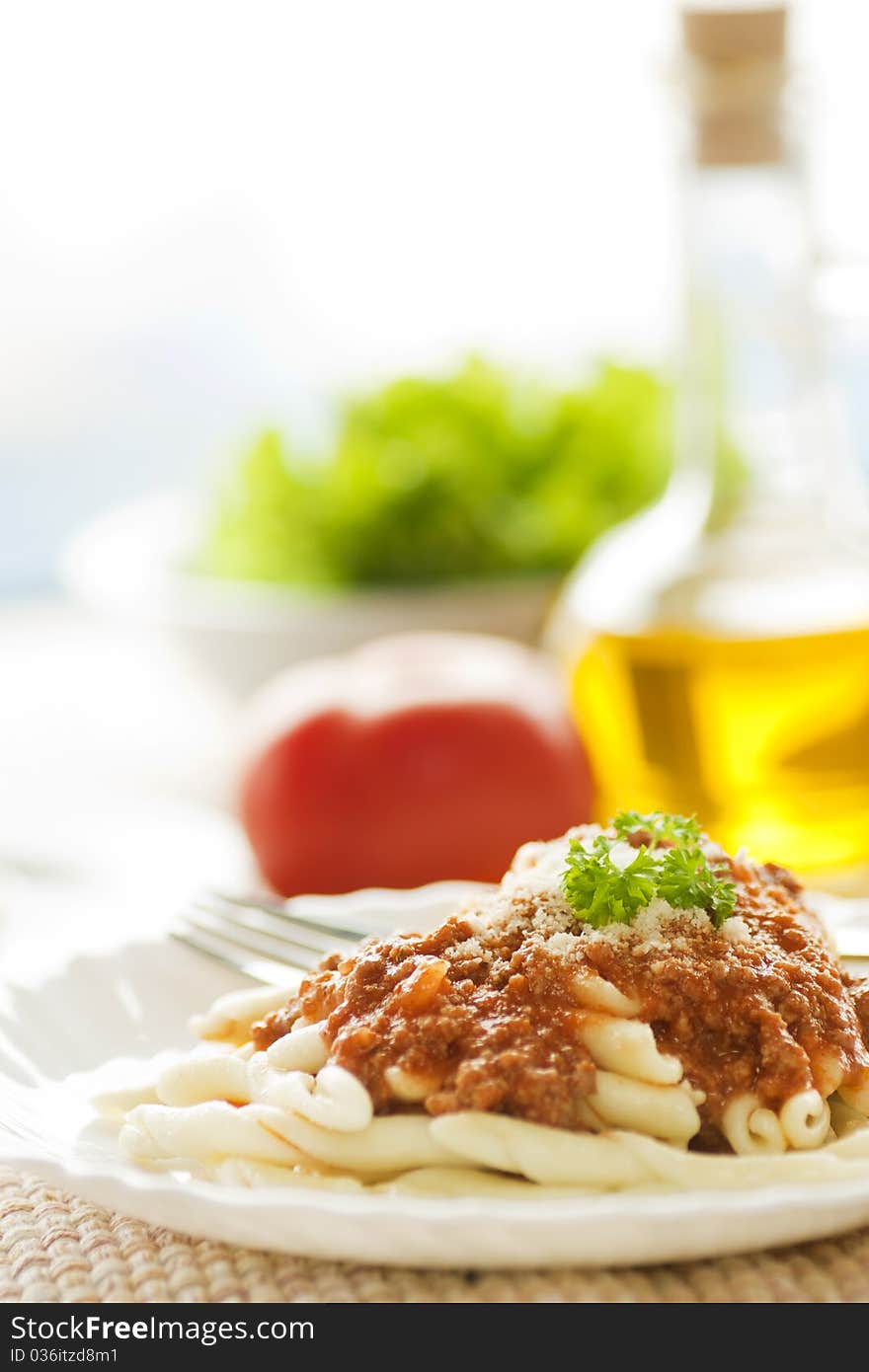 Pasta with bolognese sauce and olive oil and salad in the back