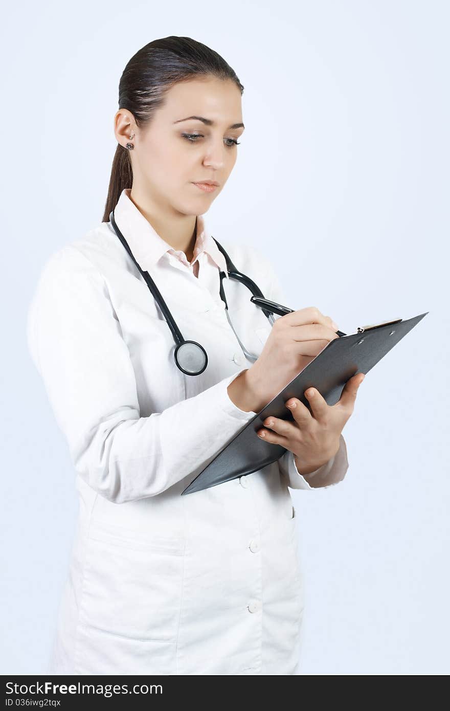 Portrait of friendly female doctor with stethoscope writes on the clipboard. Portrait of friendly female doctor with stethoscope writes on the clipboard.