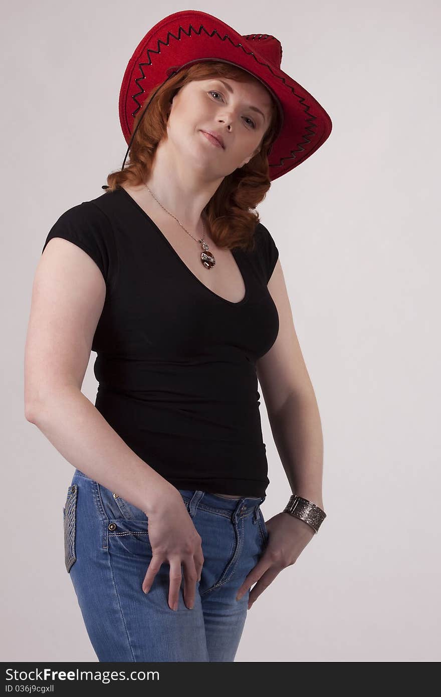 Portrait of the woman in a red cowboy's hat on a gray background