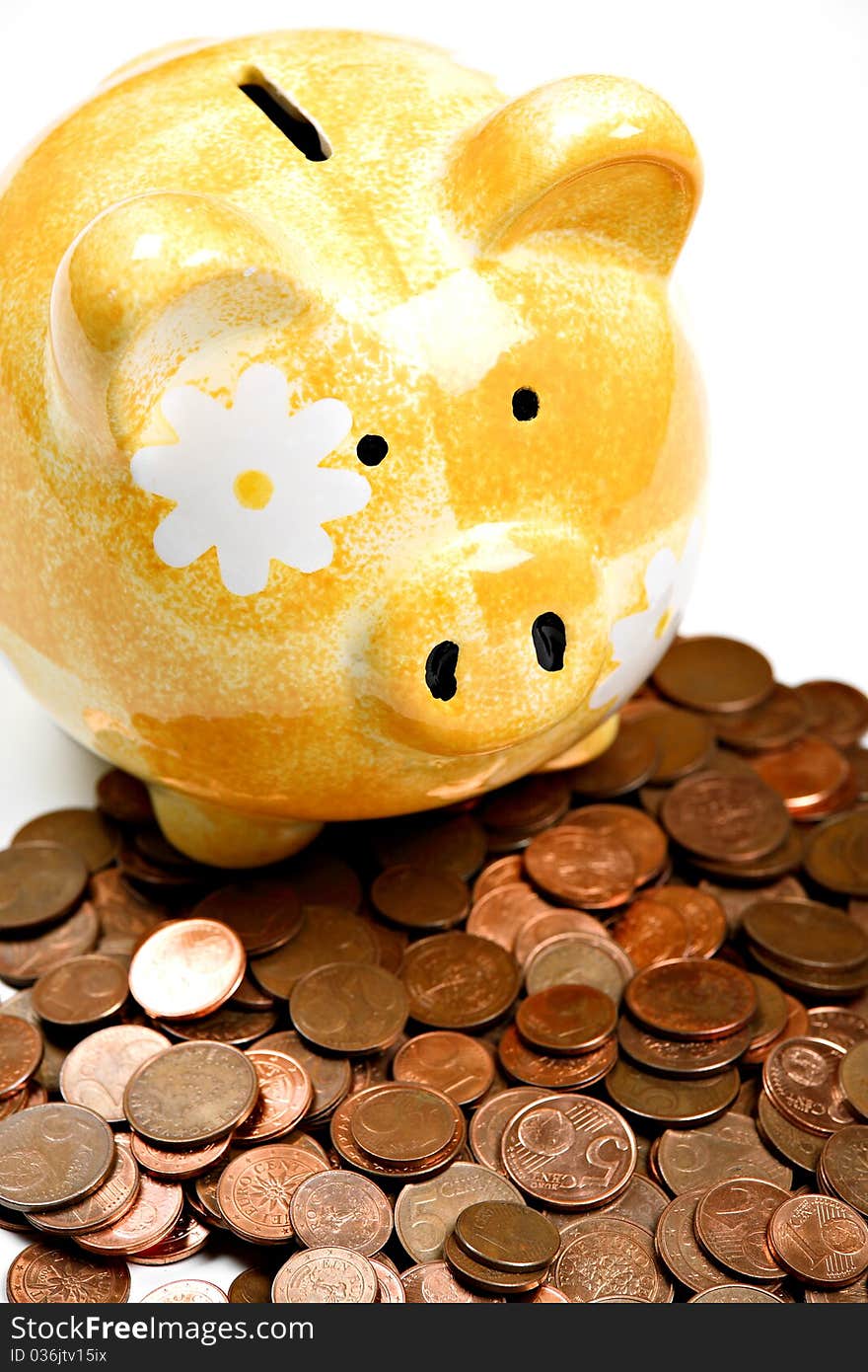 Yellow ceramic piggy bank on a pile of cents, isolated on white