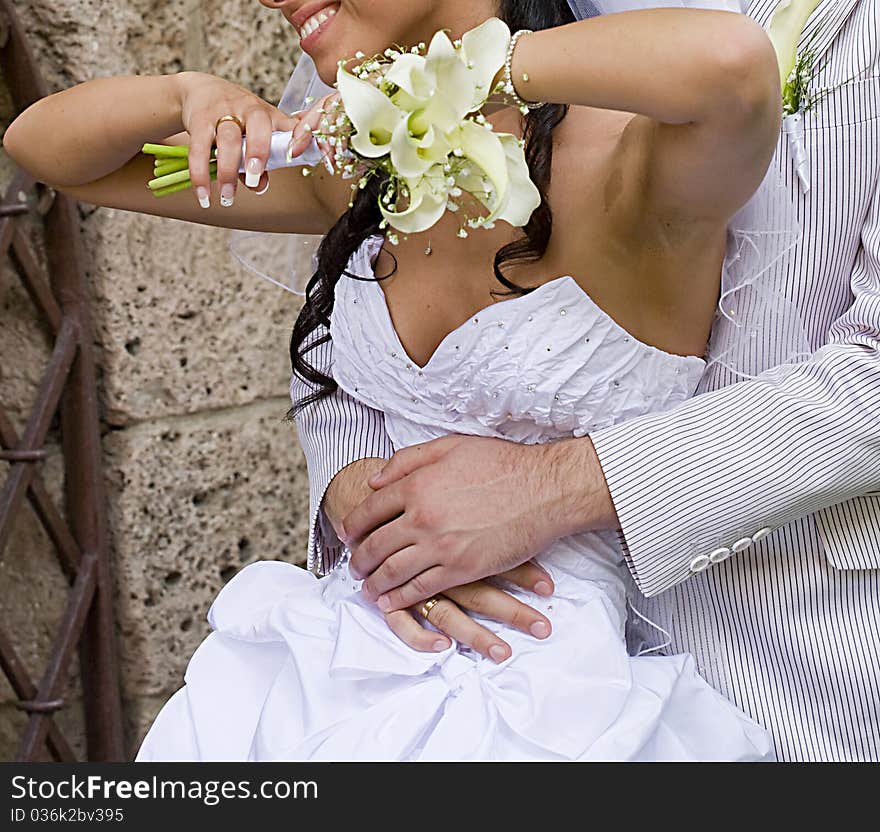 Groom hugging a smiling bride by the waist. Groom hugging a smiling bride by the waist