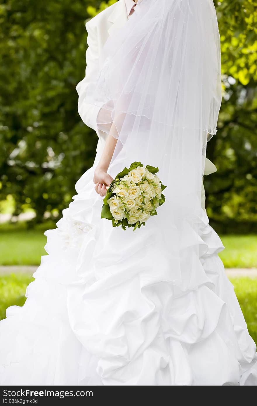 Groom embracing his bride holding a bouquet of roses. Groom embracing his bride holding a bouquet of roses