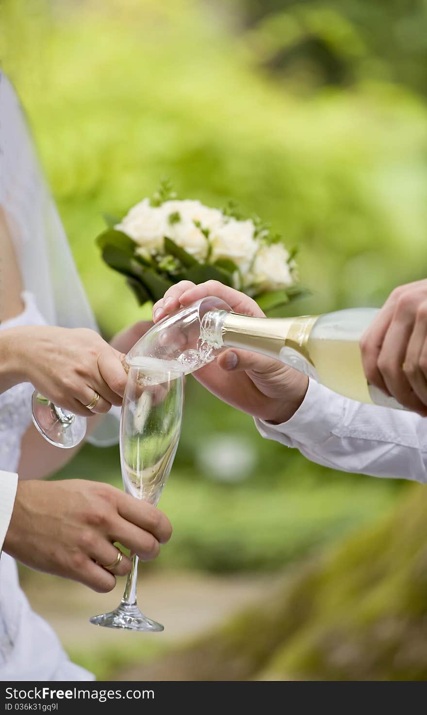 Somebody fills bride's and fiance's glasses with champagne