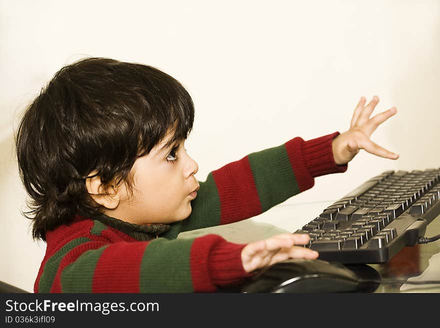 A cute little child working on his PC. A cute little child working on his PC.