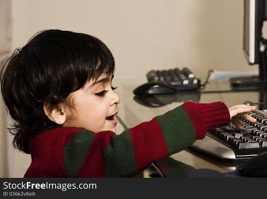 A cute little boy eating cookies and working on his PC. A cute little boy eating cookies and working on his PC.