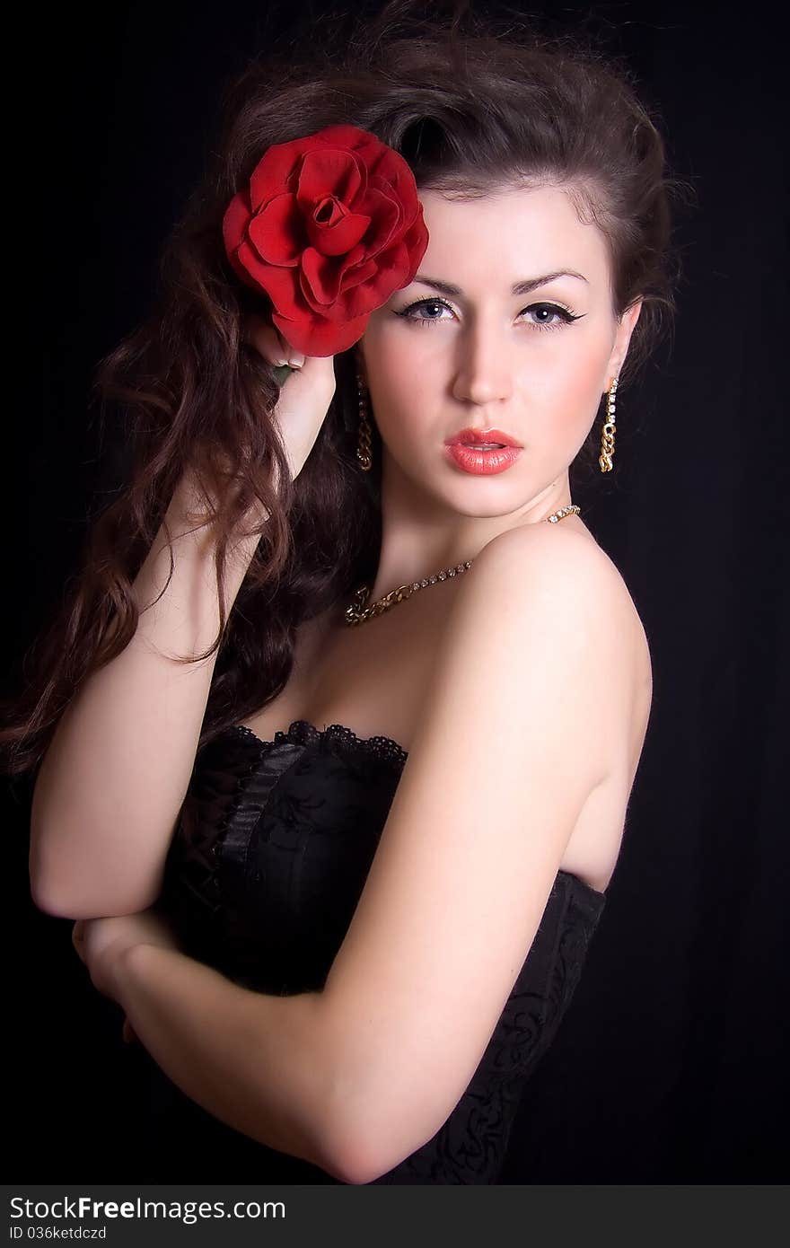 Passionate portrait of a beautiful girl with a red rose in her hair