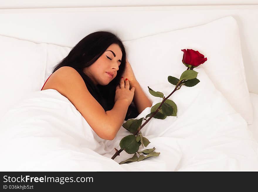 A beautiful young girl lying in bed with gifts, roses, woke up, asleep.