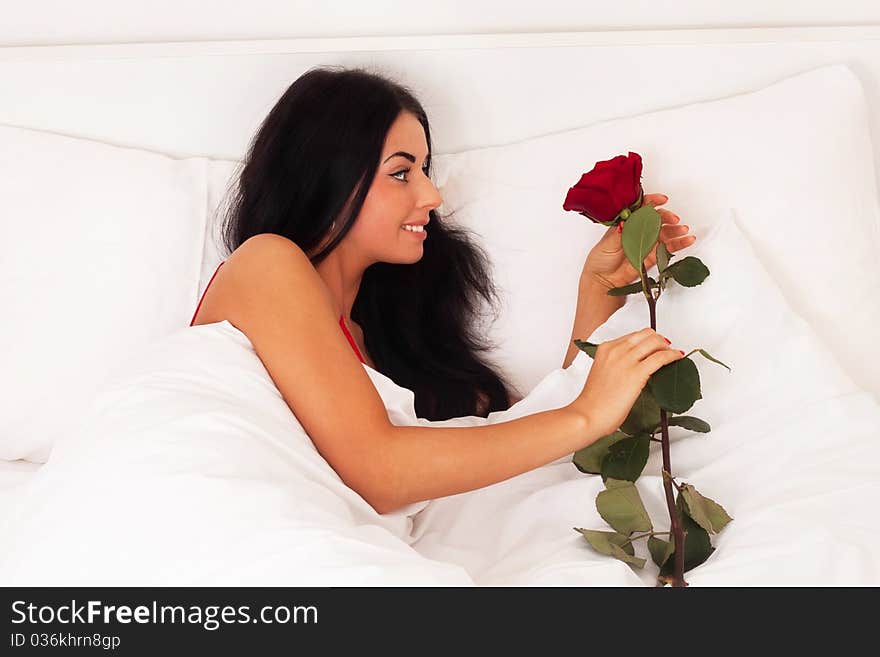 A beautiful young girl lying in bed with gifts, roses, woke up, asleep.